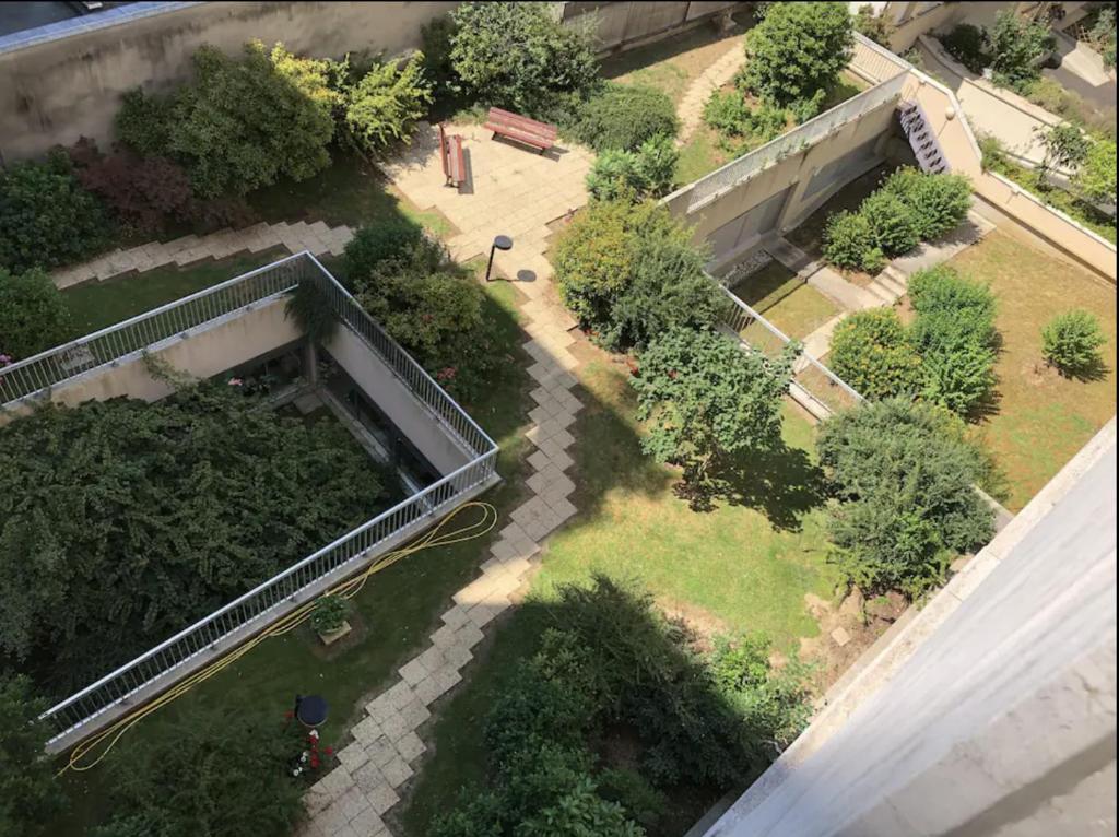 Elle offre une vue sur un jardin avec des arbres et des buissons. dans l'établissement Appartement 2 chambre proche du métro convention, à Paris