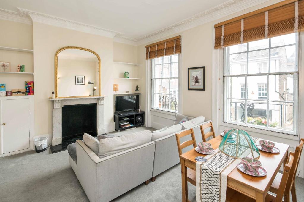 a living room with a couch and a fireplace at High-ceiling Gorgerous Victorian flat with private garden - 3 mins to Hyde Park, Kensington Palace, 8 mins NottingHill, High Street Kensington station in London
