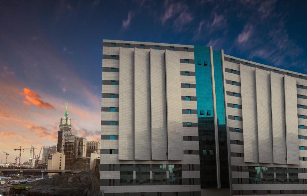 un edificio blanco alto frente a una ciudad en Saraya Al Deafah Hotel, en La Meca