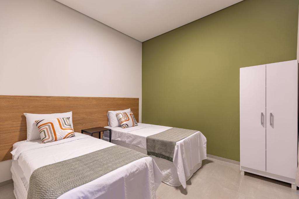 two beds in a room with green walls at Loft aconchegante com 2 Qts próximo aeroporto in Sinop