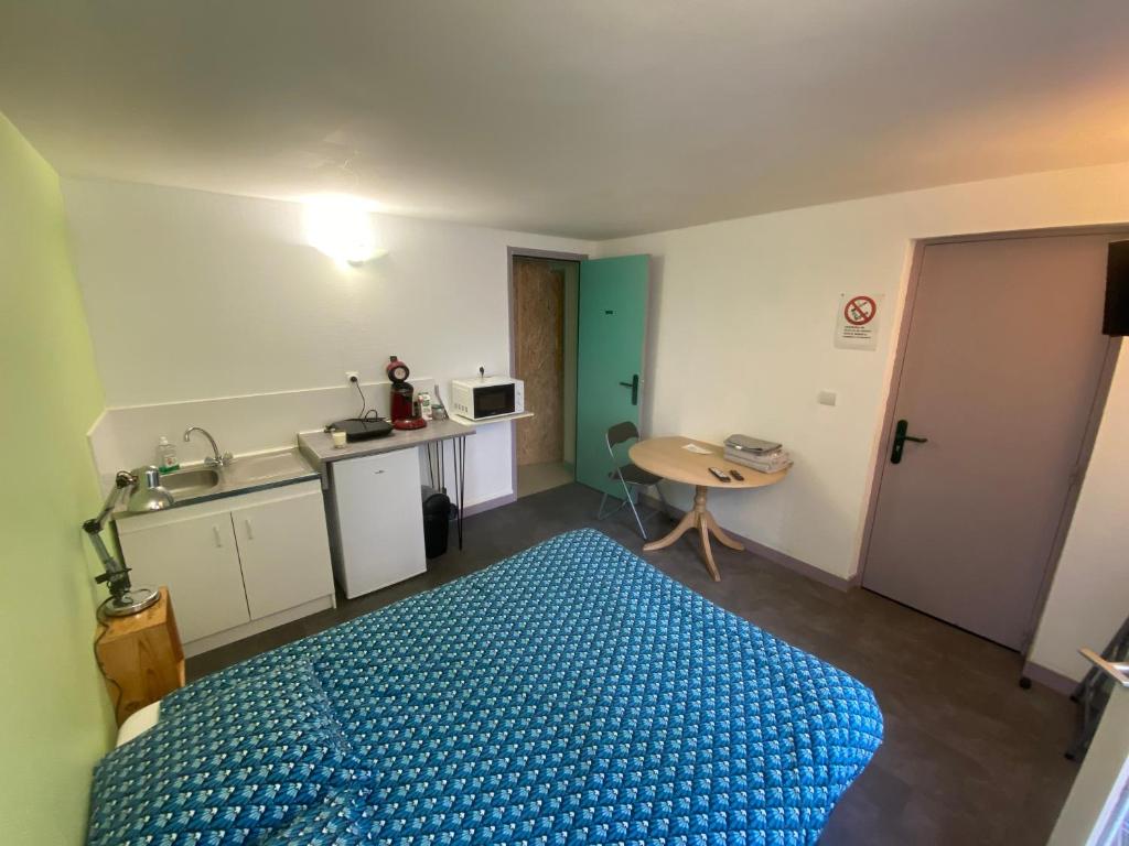 a bedroom with a blue bed and a kitchen at les moulins - studio 6 in Cherbourg en Cotentin