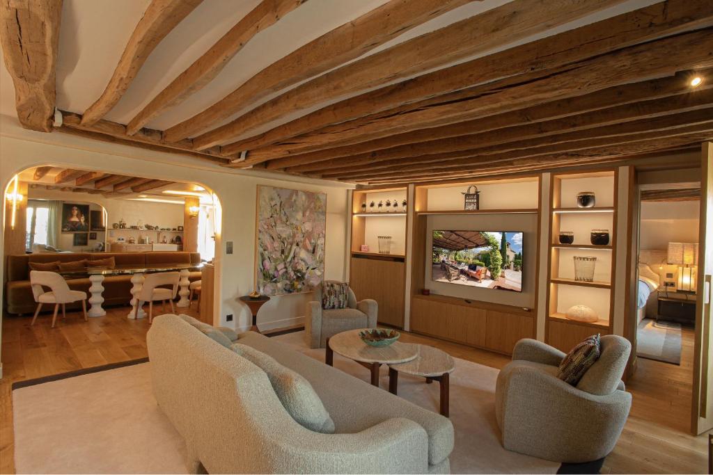 un salon avec un canapé, des chaises et une télévision dans l'établissement Luxueux Appartement, avec terrasse vue Champs-Élysées, à Paris
