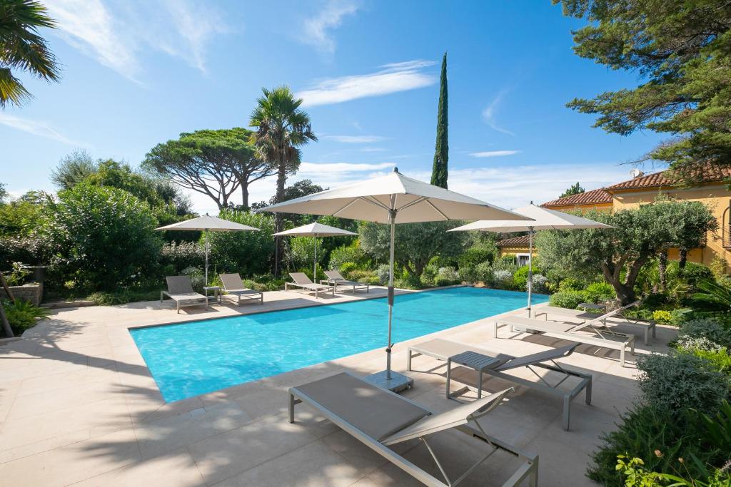 une piscine avec chaises longues et parasols dans l'établissement Villa Azzurra Front Beach - Happy Rentals, à Saint-Tropez