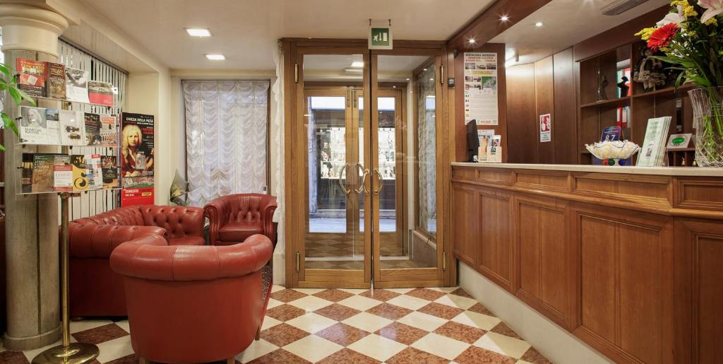 una sala de espera con una silla de cuero y un bar en Hotel Commercio & Pellegrino en Venecia