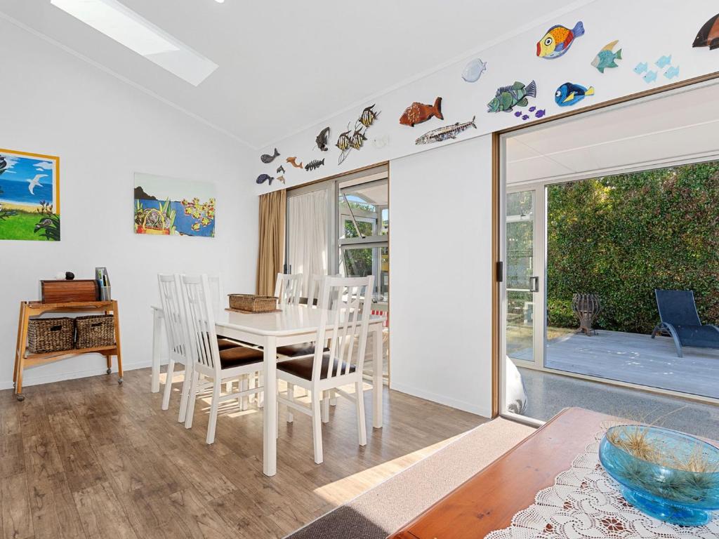 una sala da pranzo con tavolo e sedie bianchi di Ruakaka Holiday Escape - Ruakaka Holiday Home a Ruakaka