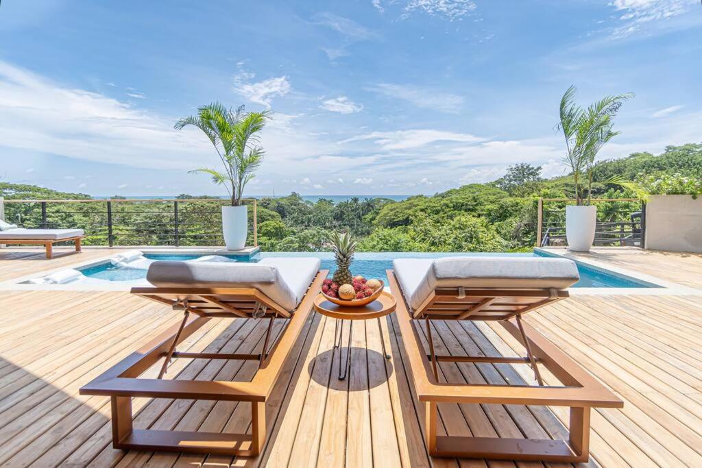 una terraza de madera con 2 sillas y una piscina en Blanko Mar Ocean view, en Santa Teresa Beach