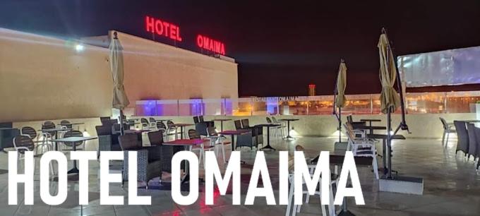 un gruppo di tavoli e sedie di fronte a un edificio di Hotel OMAIMA a Laayoune
