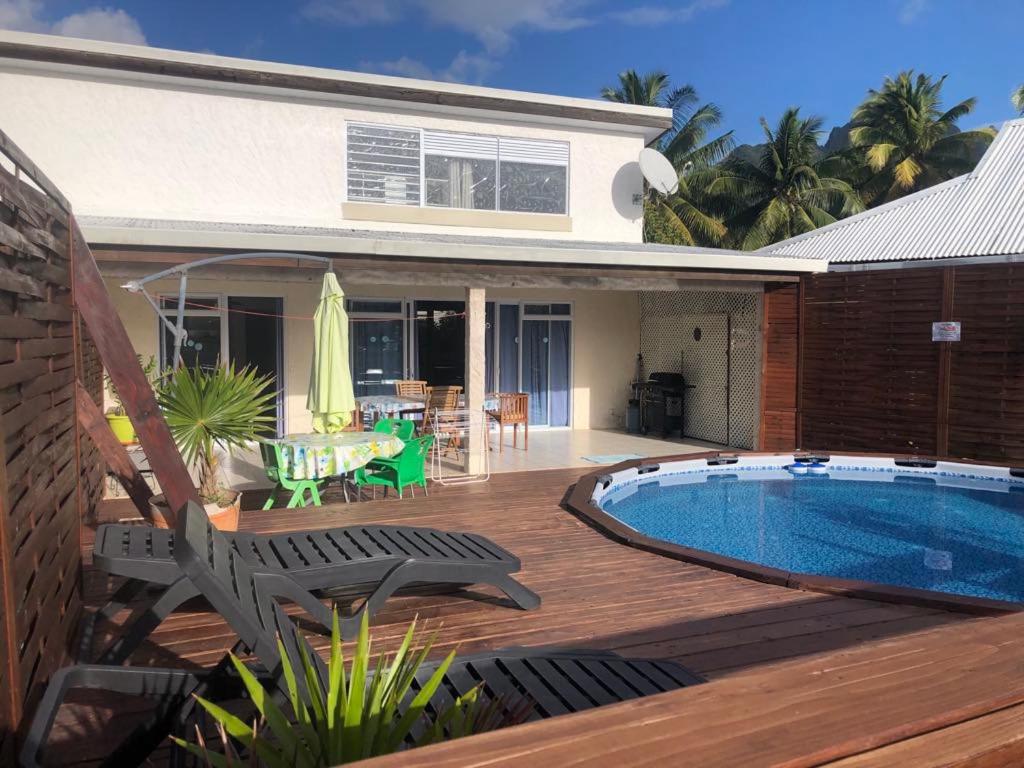 a house with a deck and a swimming pool at Lodge Moorea Vaikea in Papetoai