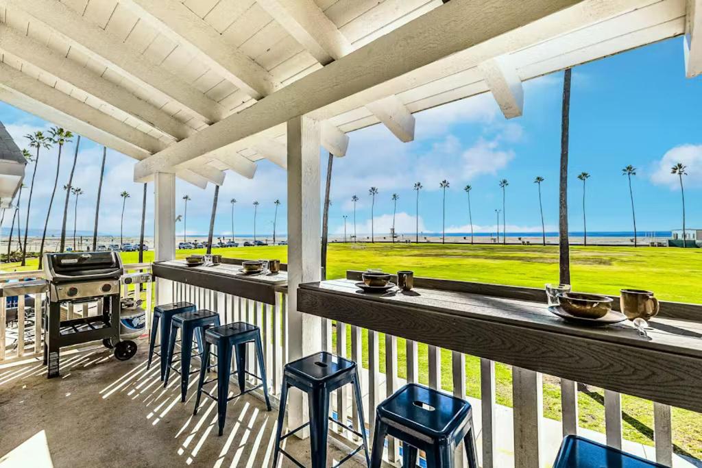 a porch with stools and a bar with a view of the ocean at Stunning 2nd Floor Beachfront Home with Balcony, Ocean Views, and Prime Location in Newport Beach