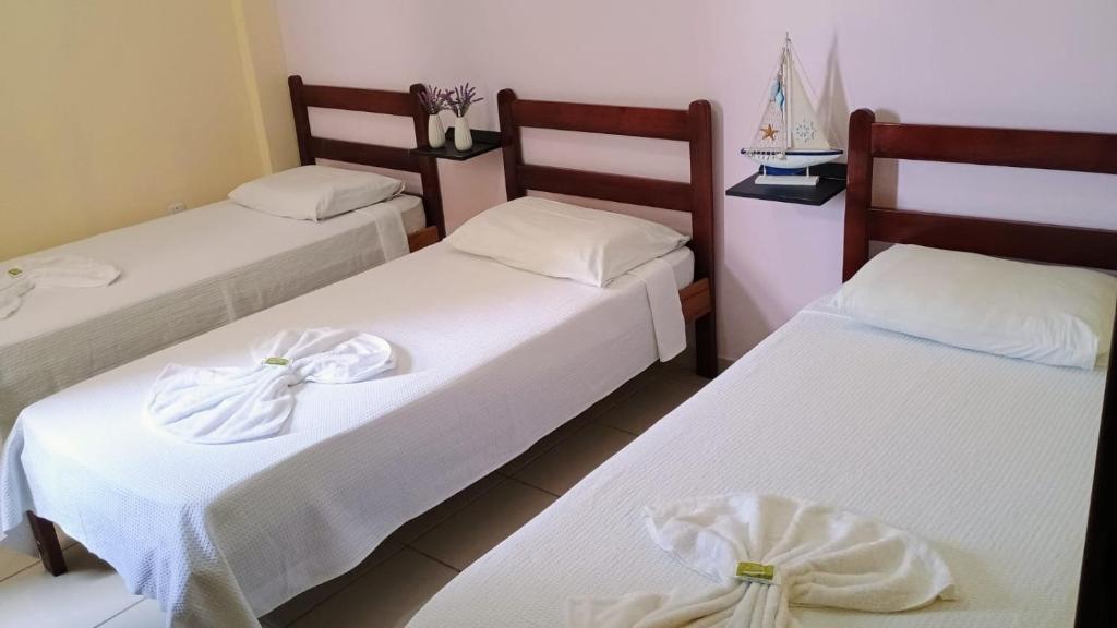 a room with two beds with white sheets at Pousada Brisa do Mar in Aracruz