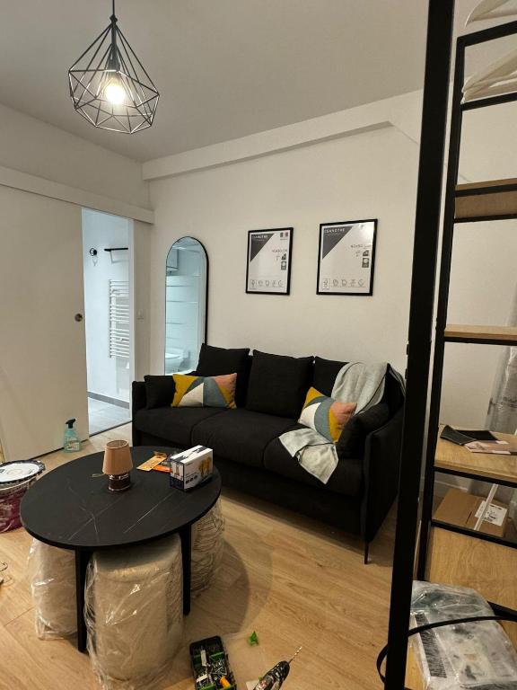 un salon avec un canapé noir et une table dans l'établissement Oberkampf by Melvane 21, à Paris