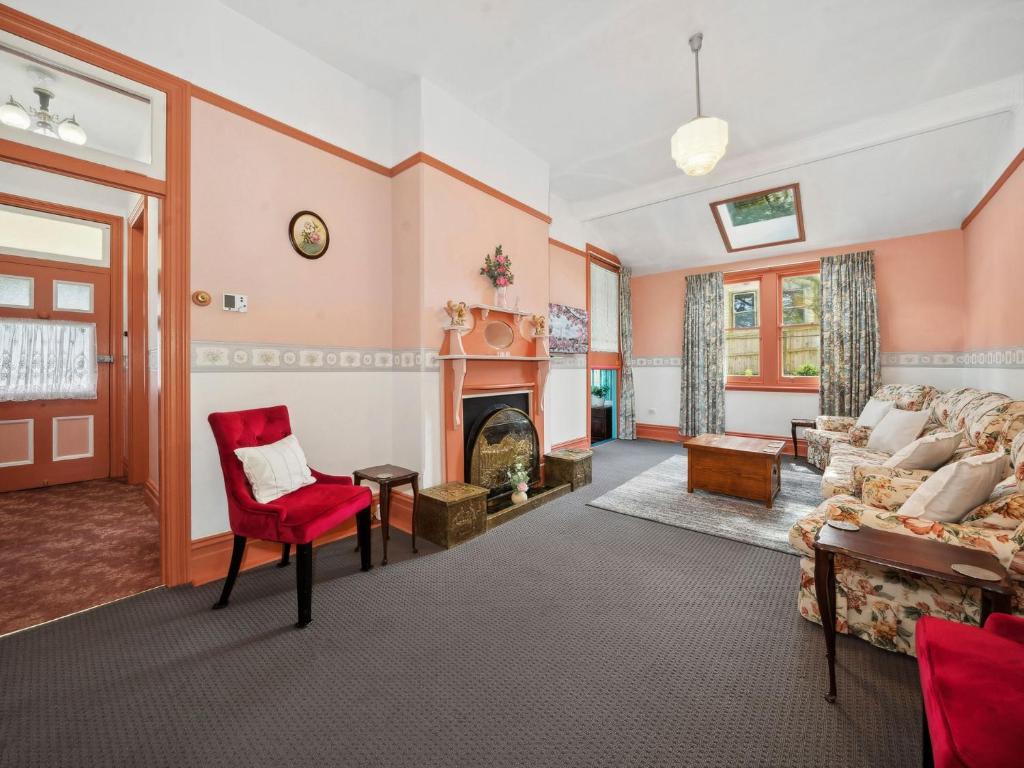 a living room with a red chair and a fireplace at The Outlook in Leura