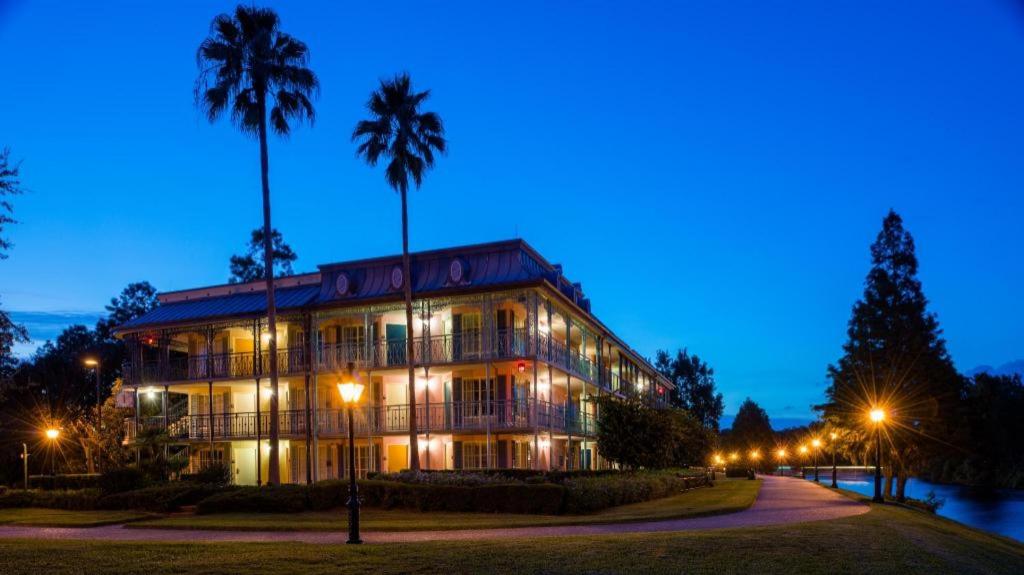a building at night with palm trees and lights at Disney's Port Orleans Resort - French Quarter in Orlando