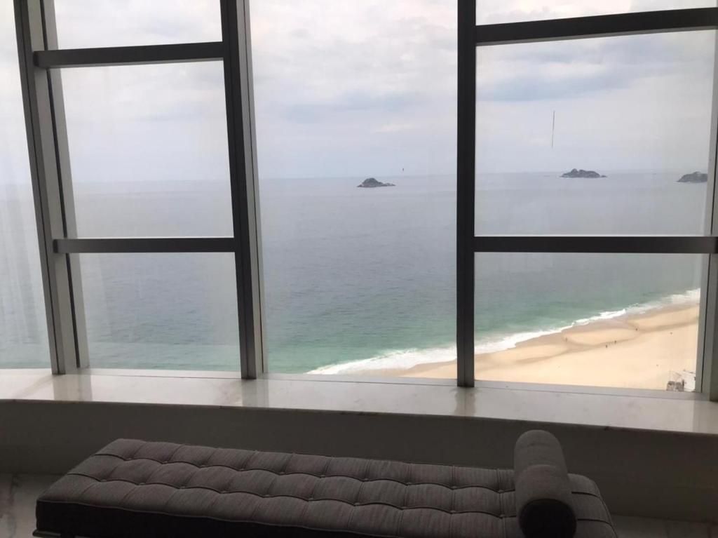 a view of a beach from a window with a couch at Hotel Nacional Rio de Janeiro in Rio de Janeiro