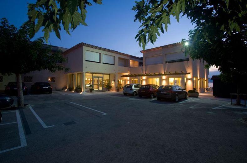 a large building with cars parked in a parking lot at Au Tapis de Sable in Saint-Cyr-sur-Mer