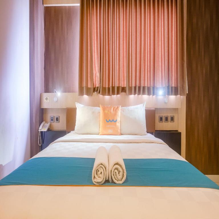 Postel nebo postele na pokoji v ubytování Sans Hotel Grand Omah Sastro Yogyakarta