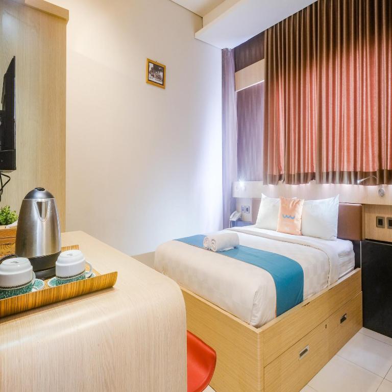 Postel nebo postele na pokoji v ubytování Sans Hotel Grand Omah Sastro Yogyakarta