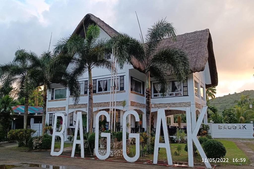 a house with palm trees in front of it at Baggak Hotel & Restaurant by SMS Hospitality in Sanchez-Mira