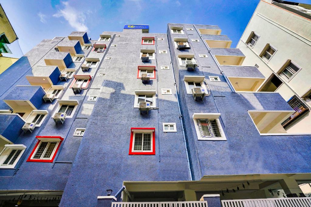 LingampalliFabExpress Grand Aarvi Prime - Nr GSM Mall, Madeenaguda的一座高大的蓝色建筑,设有红色窗户