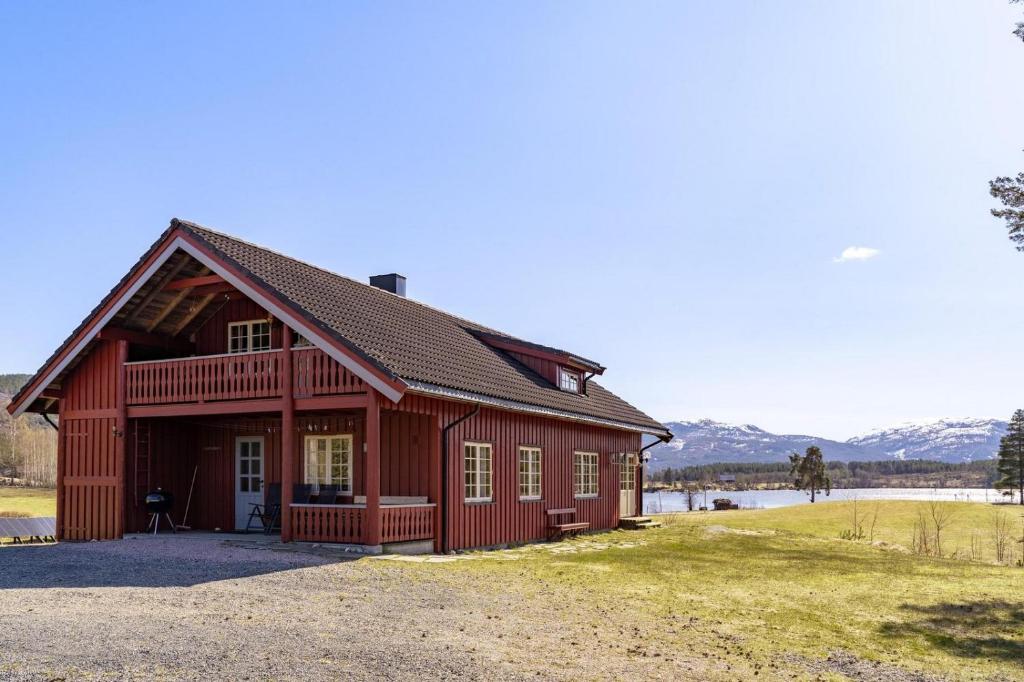 a red barn with mountains in the background at Storhytta - 16p - Norwegian nostalgia by the water in Vradal