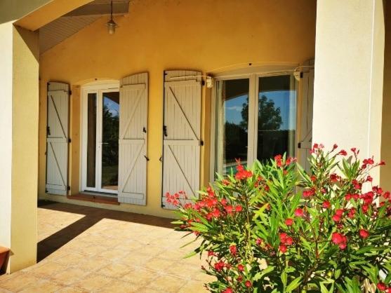 une maison avec des portes blanches et des fleurs rouges devant dans l'établissement Bel appartement T2 meublé proche de Toulouse, à Mondonville