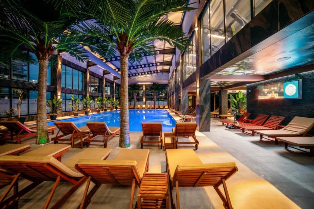a hotel lobby with tables and chairs and a swimming pool at Hotel Nordic Twins & Wellness in Rădăuţi