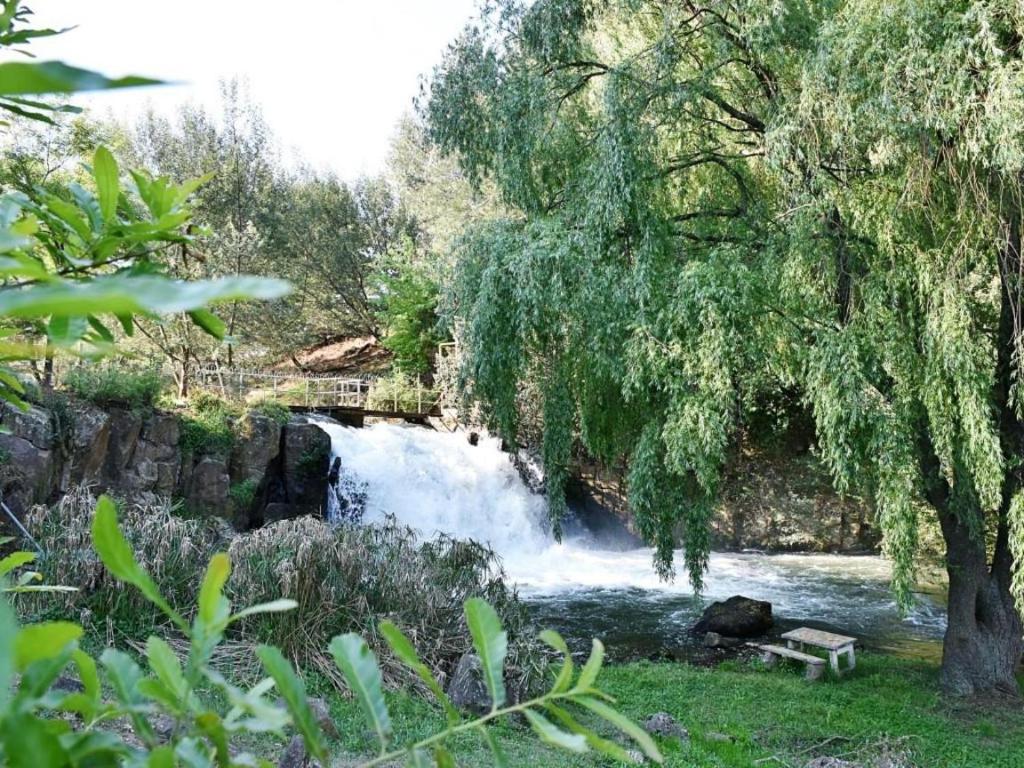 a river with a bench in front of a waterfall at The Falls Cottages in Balgowan