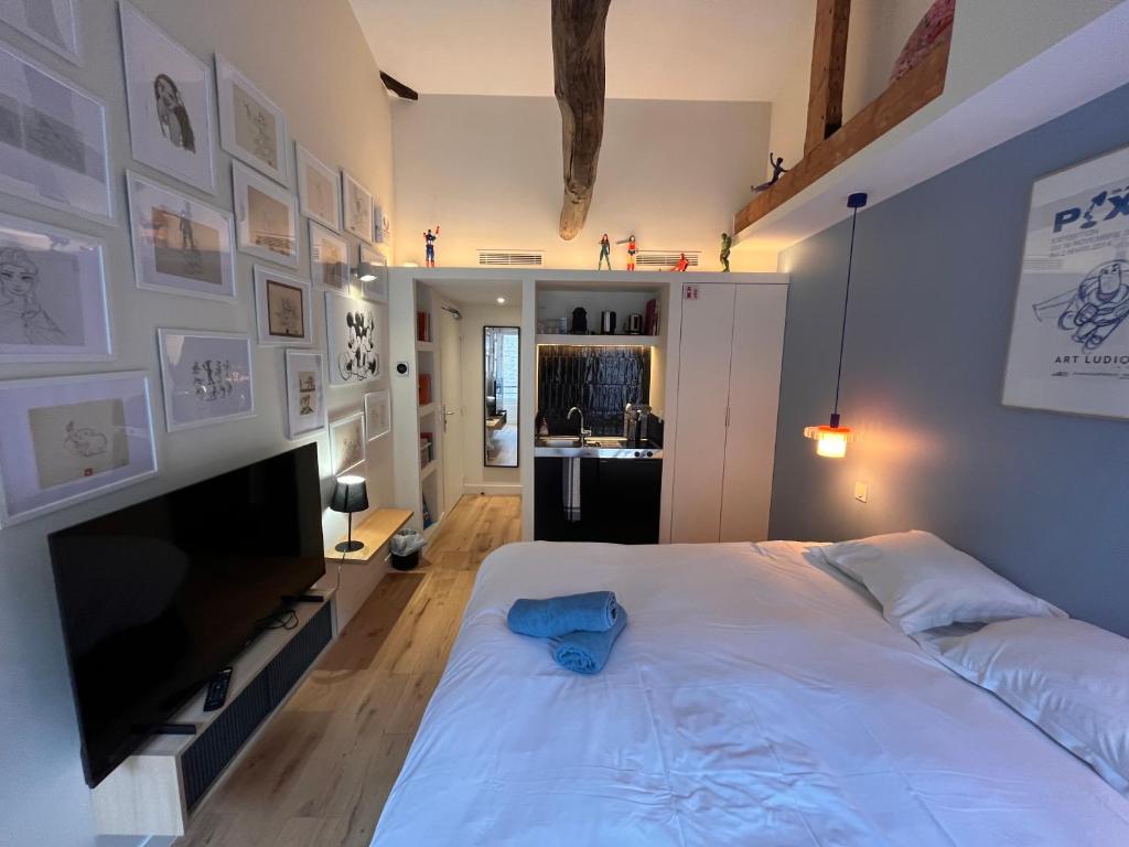 - une chambre avec un grand lit blanc et une télévision à écran plat dans l'établissement Saint Jacques Disney, à Paris