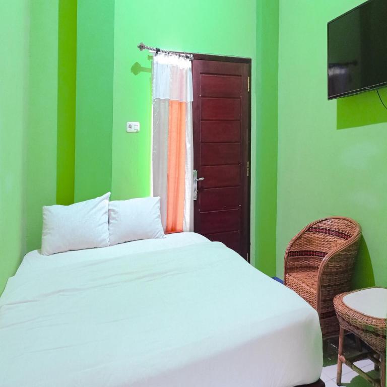 a bed in a room with green walls and a window at Hotel Pabelan RedPartner in Bengkulu