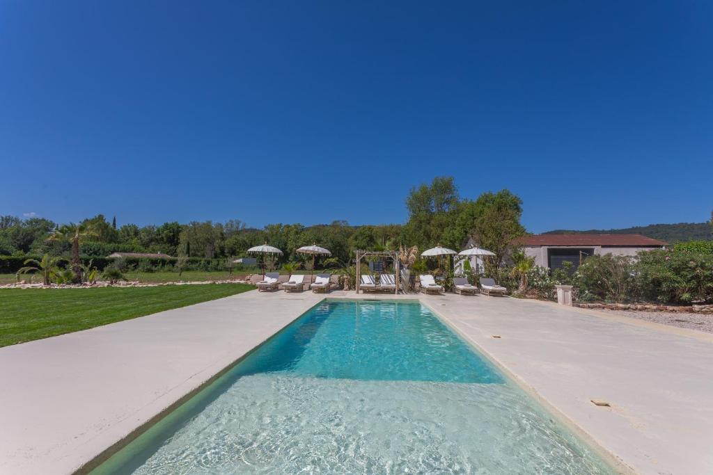 a swimming pool with chairs and umbrellas in a yard at Domaine Montserrat in Le Luc