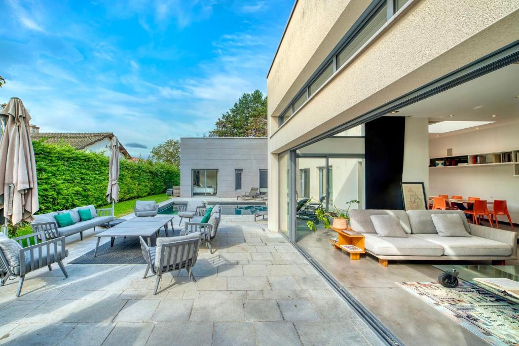 un patio avec un canapé, une table et des chaises dans l'établissement L'Avedis - Magnifique maison de luxe avec piscine, à Montanay