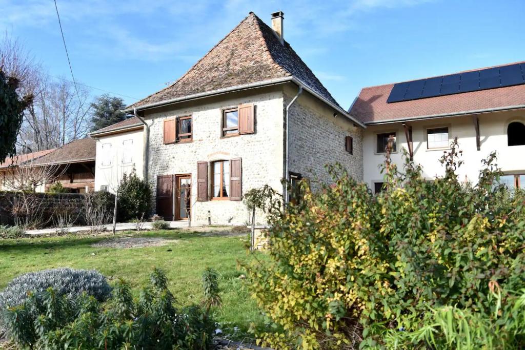 une maison ancienne avec des panneaux solaires sur le toit dans l'établissement Gîte La Petite Dauphinoise, à Gillonnay