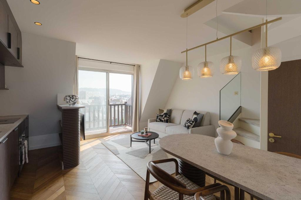une cuisine et un salon avec une table et un canapé dans l'établissement High-end 2 bedroom duplex with parking Place Morny, à Deauville