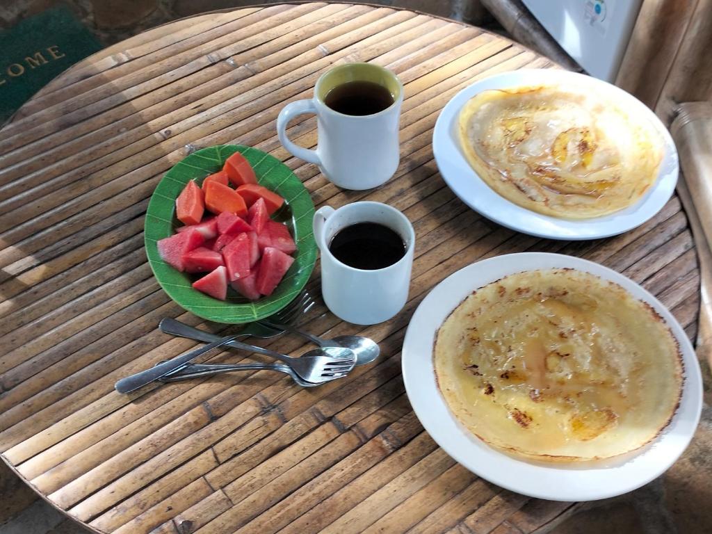 un tavolo con due piatti di cibo e un cesto di frutta di Bamboohouse pondok salacca #salacca inn a Manggis