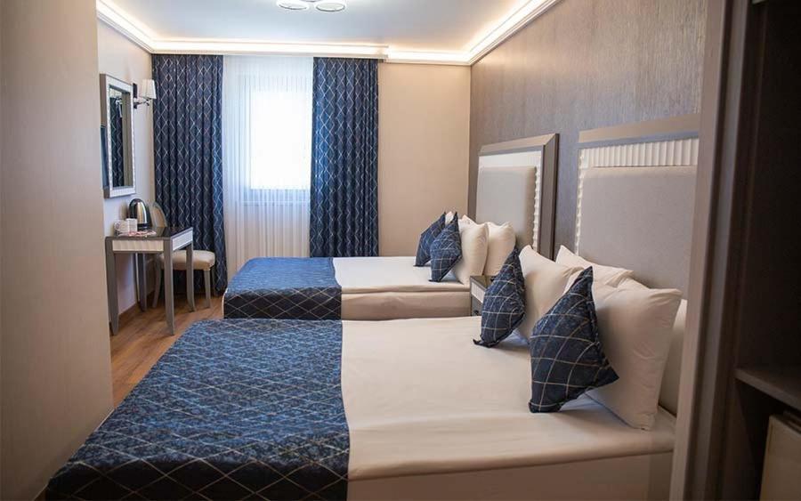 a hotel room with two beds with blue pillows at Mineo Park Hotel in Istanbul