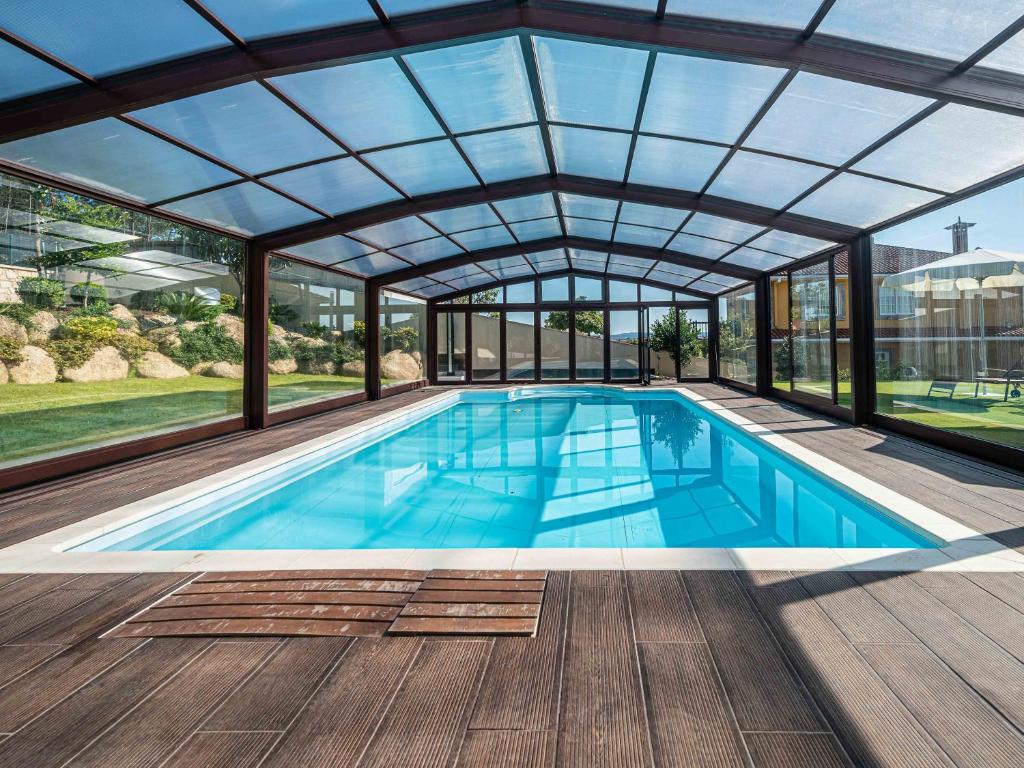 an indoor swimming pool with a glass ceiling at Lujo a estrenar con piscina cubierta in Teo