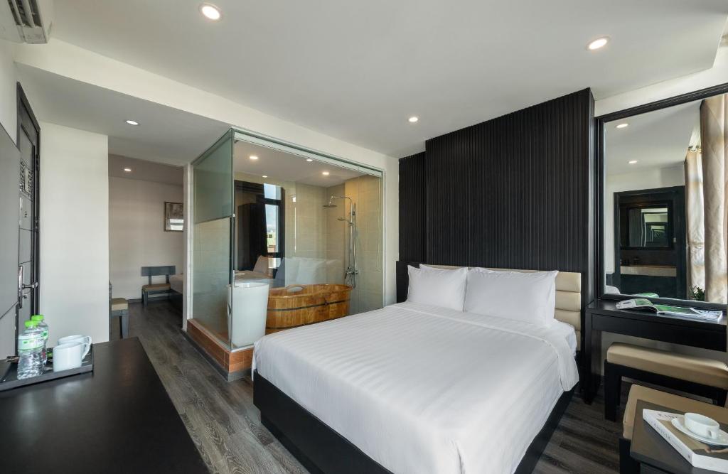 A modern bedroom with a large bed and a glass-walled bathroom beside it.