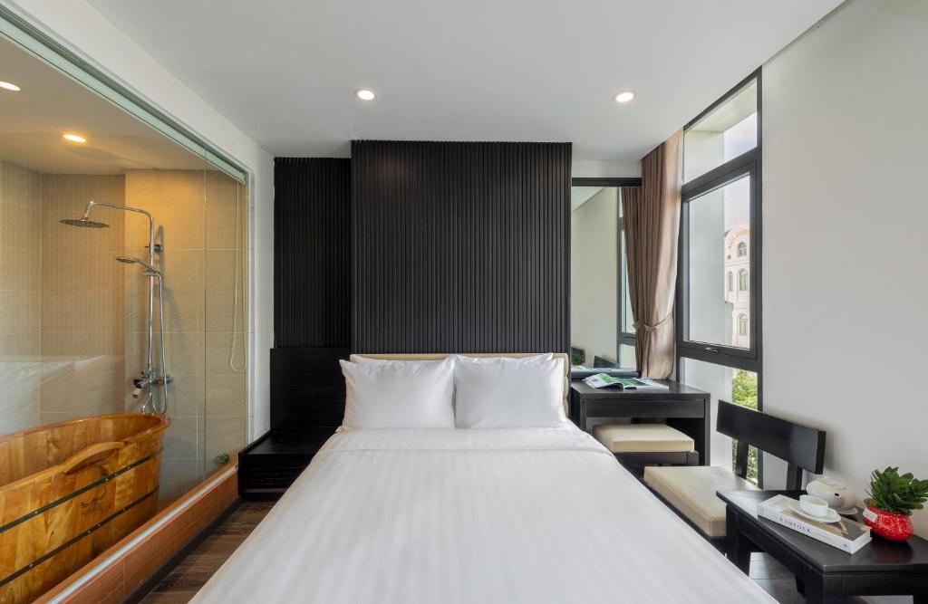 A compact bedroom with a large bed, glass bathroom, bathtub and sea-facing window.