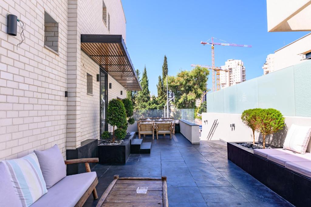 an outdoor patio with a couch and tables on a building at Rokah Luxury Villa at Ramat HaHayal in Tel Aviv