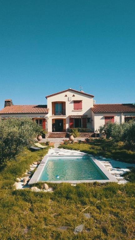 une maison avec une piscine devant dans l'établissement Grande villa catalane dans parc aux oliviers, à Ortaffa