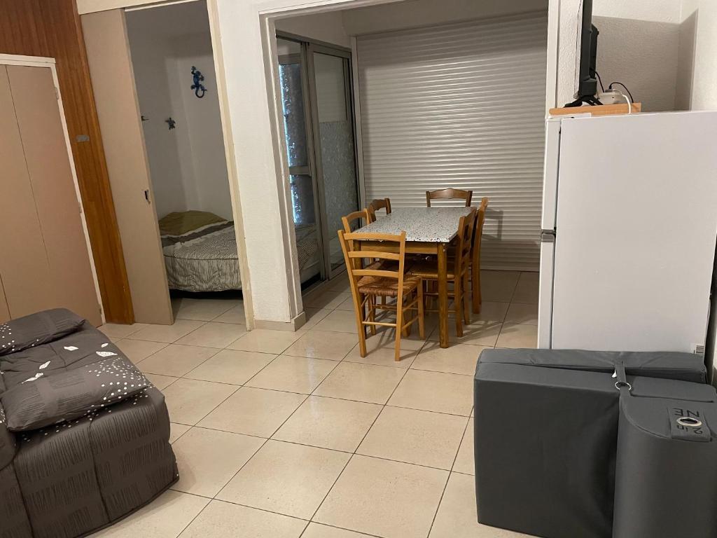 une cuisine avec une table, des chaises et un réfrigérateur dans l'établissement Cap près port commerces, au Cap d'Agde