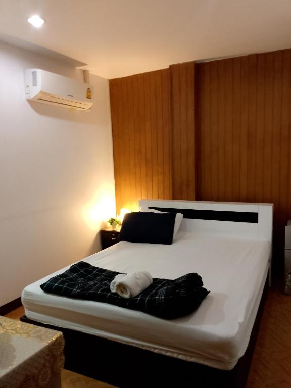 a bedroom with a large white bed with a black blanket at Lucky Guest house in Karon Beach