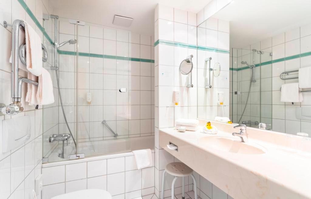 a white bathroom with a sink and a shower at Strandhotel Sylt Westerland in Westerland