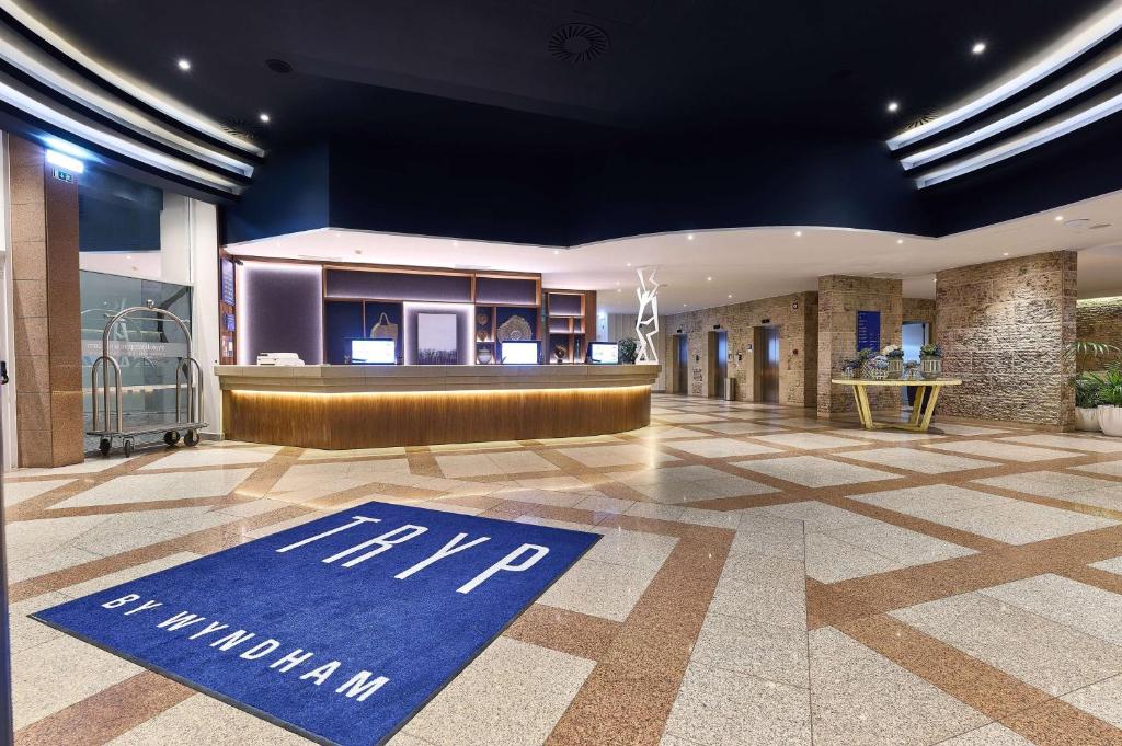 a lobby with a blue sign on the floor of a building at TRYP by Wyndham Lisboa Caparica Mar in Costa da Caparica