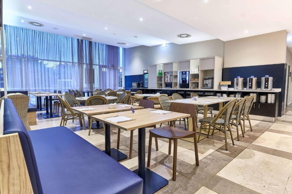 a restaurant with wooden tables and chairs and windows at TRYP by Wyndham Lisboa Caparica Mar in Costa da Caparica
