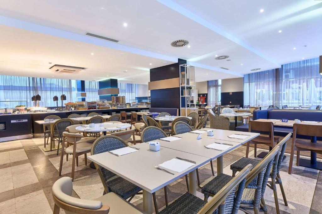 a restaurant with tables and chairs and a bar at TRYP by Wyndham Lisboa Caparica Mar in Costa da Caparica