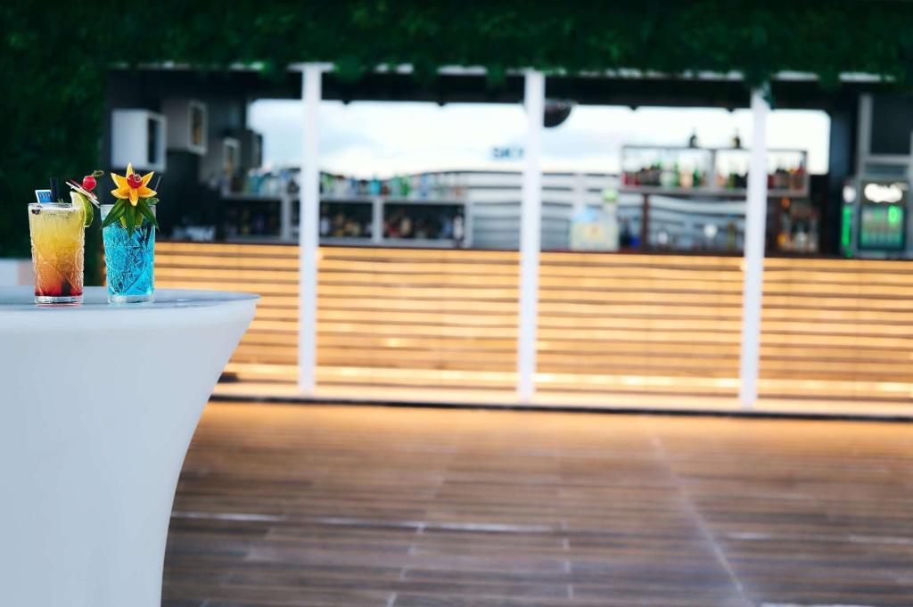 a table with a drink and a flower in a vase at TRYP by Wyndham Lisboa Caparica Mar in Costa da Caparica