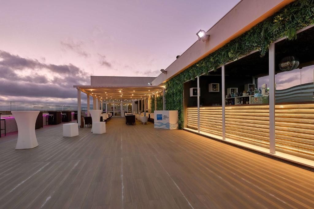 a rooftop deck with white tables and chairs at TRYP by Wyndham Lisboa Caparica Mar in Costa da Caparica