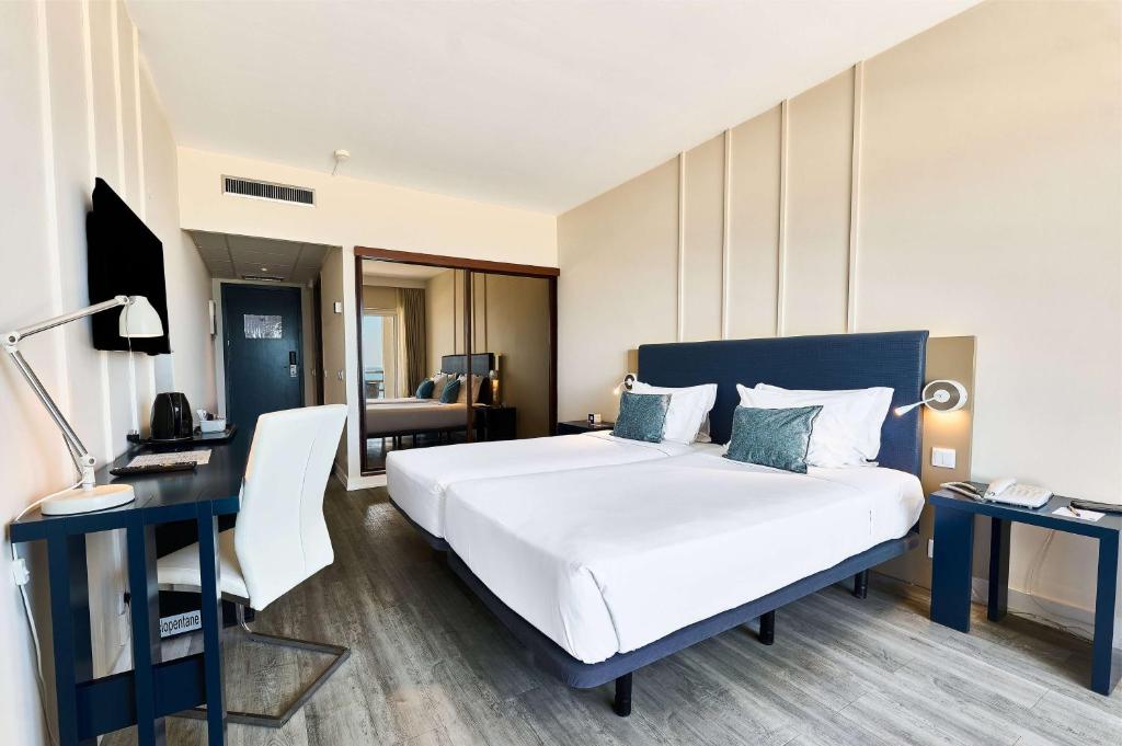 a hotel room with a bed and a desk with a phone at TRYP by Wyndham Lisboa Caparica Mar in Costa da Caparica