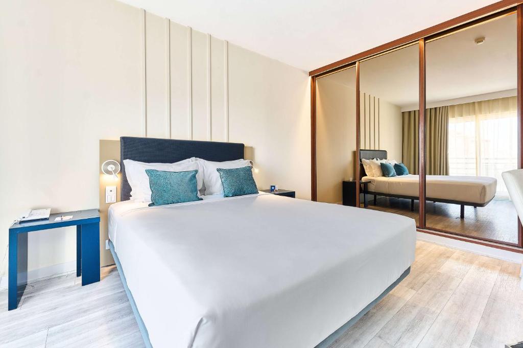 a bedroom with a large white bed and a couch at TRYP by Wyndham Lisboa Caparica Mar in Costa da Caparica